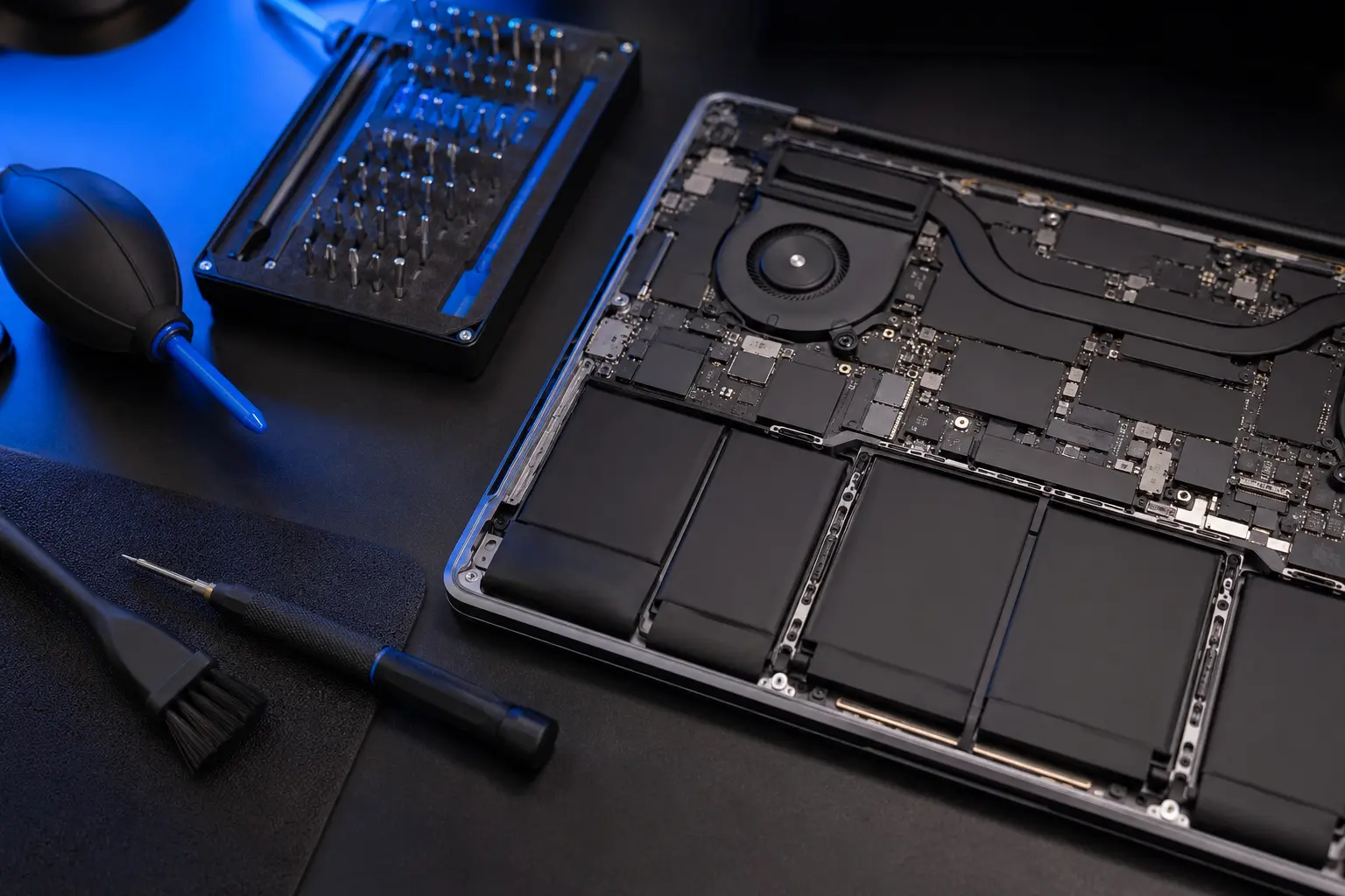 Open laptop internals and precision repair tools on a professional workbench